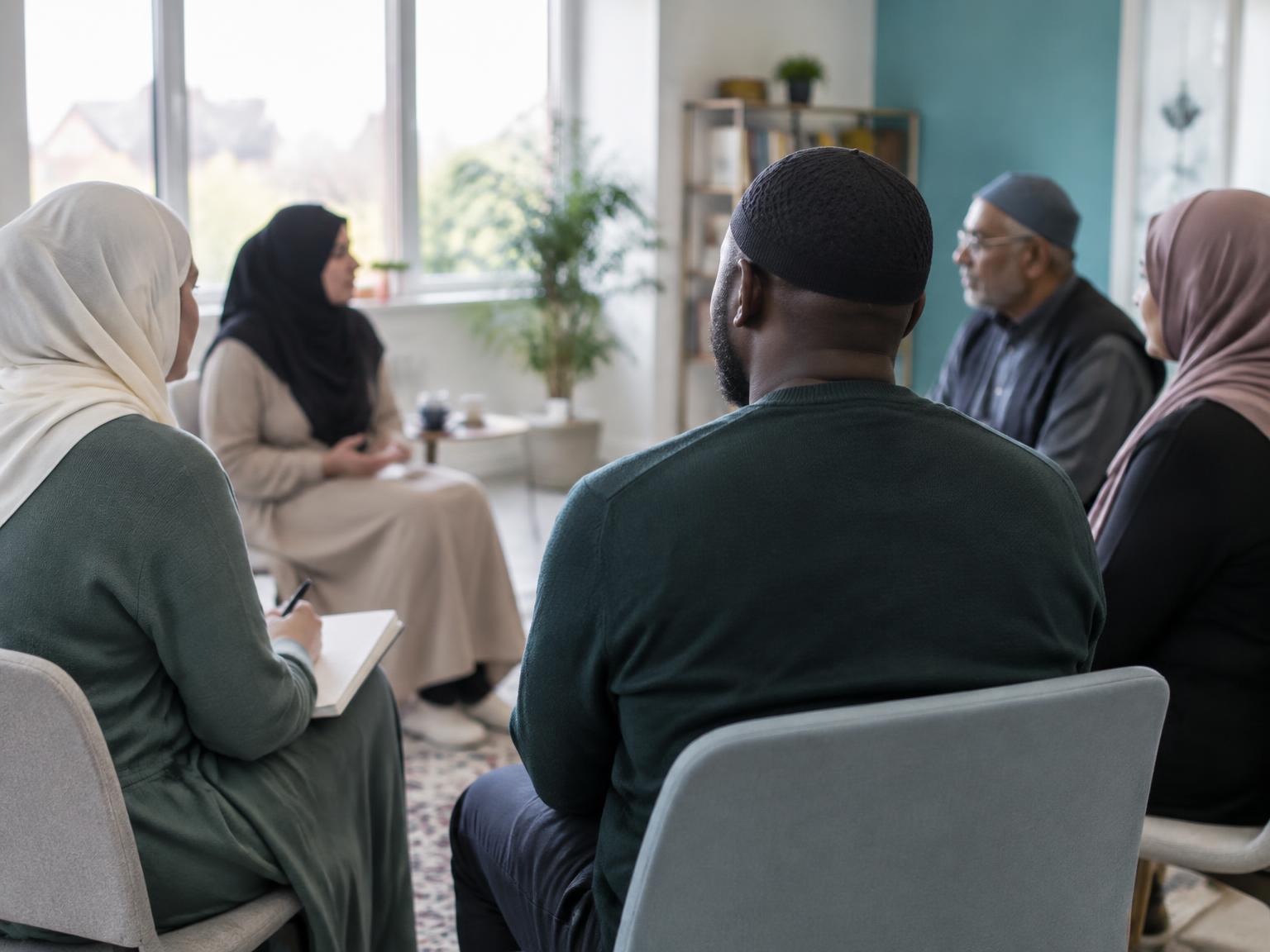 A diverse group of Muslim parents learning together, photographed mainly from behind